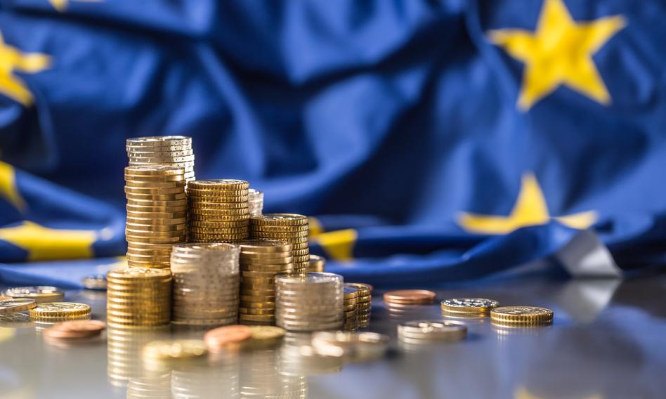 na obrazku sa monety ułożone w słupki a z tyłu flaga ue